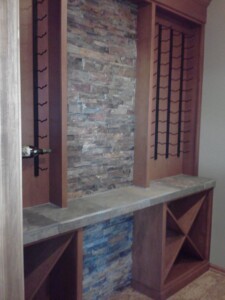 Empty wine rack with a stone accent wall and wooden shelves, featuring a single bottle on the left.