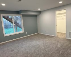 A carpeted room with recessed lighting, a large window, and a doorway leading to a closet.