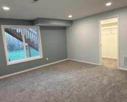 A carpeted room with recessed lighting, a large window, and a doorway leading to a closet.
